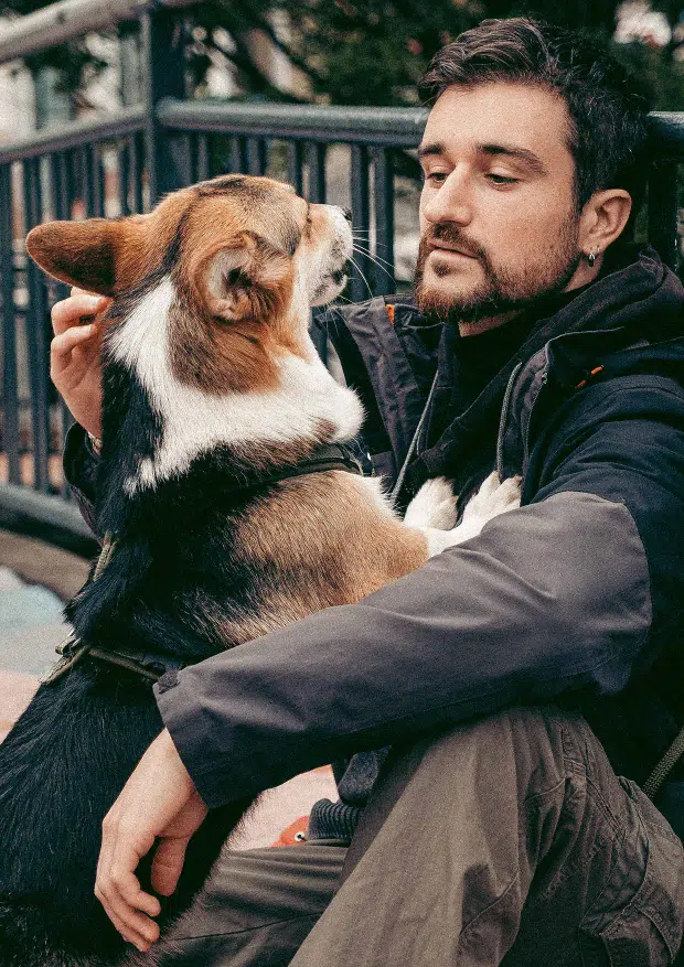 Camille Proust, éducateur canin à Toulouse, assis au sol en échange de regards profonds avec sa chienne Plùm, dans un moment de connexion et d’écoute mutuelle.