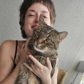 Portrait d’une femme tenant dans ses bras un chat tigré.